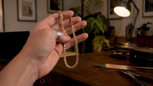 Close-up of hand holding gold Franco chain necklace