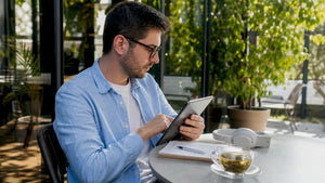 Man browsing gold chain alternatives on tablet in café