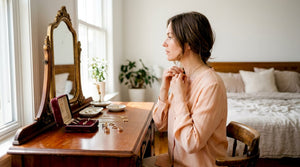 Woman adjusting gold necklace at dressing table