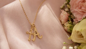 14K gold pendant necklace on fabric with flowers