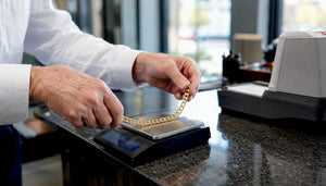 Hands weighing gold chain on digital scale
