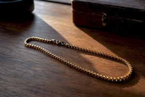 Close-up of gold box chain links on stone