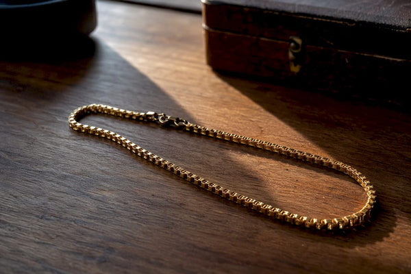 Close-up of gold box chain links on stone