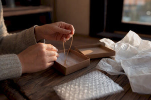 Hands packing gold chain into jewelry box