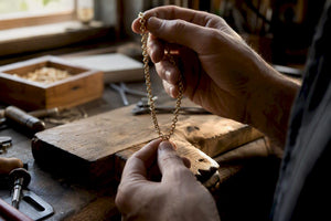 Close-up of hands examining gold chain links
