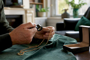 Hands inspecting gold chain with loupe