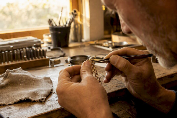 Close-up of hands inspecting gold chain clasp